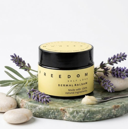 Jar of 'Freedom' dermal balsam with lavender and stones on a white background