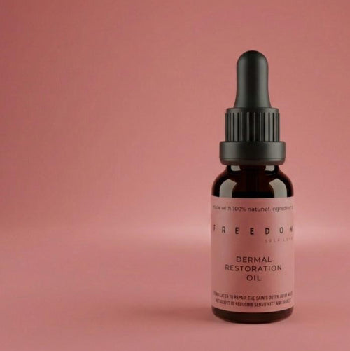 Bottle of Freedom Dermal Restoration Oil on a pink background